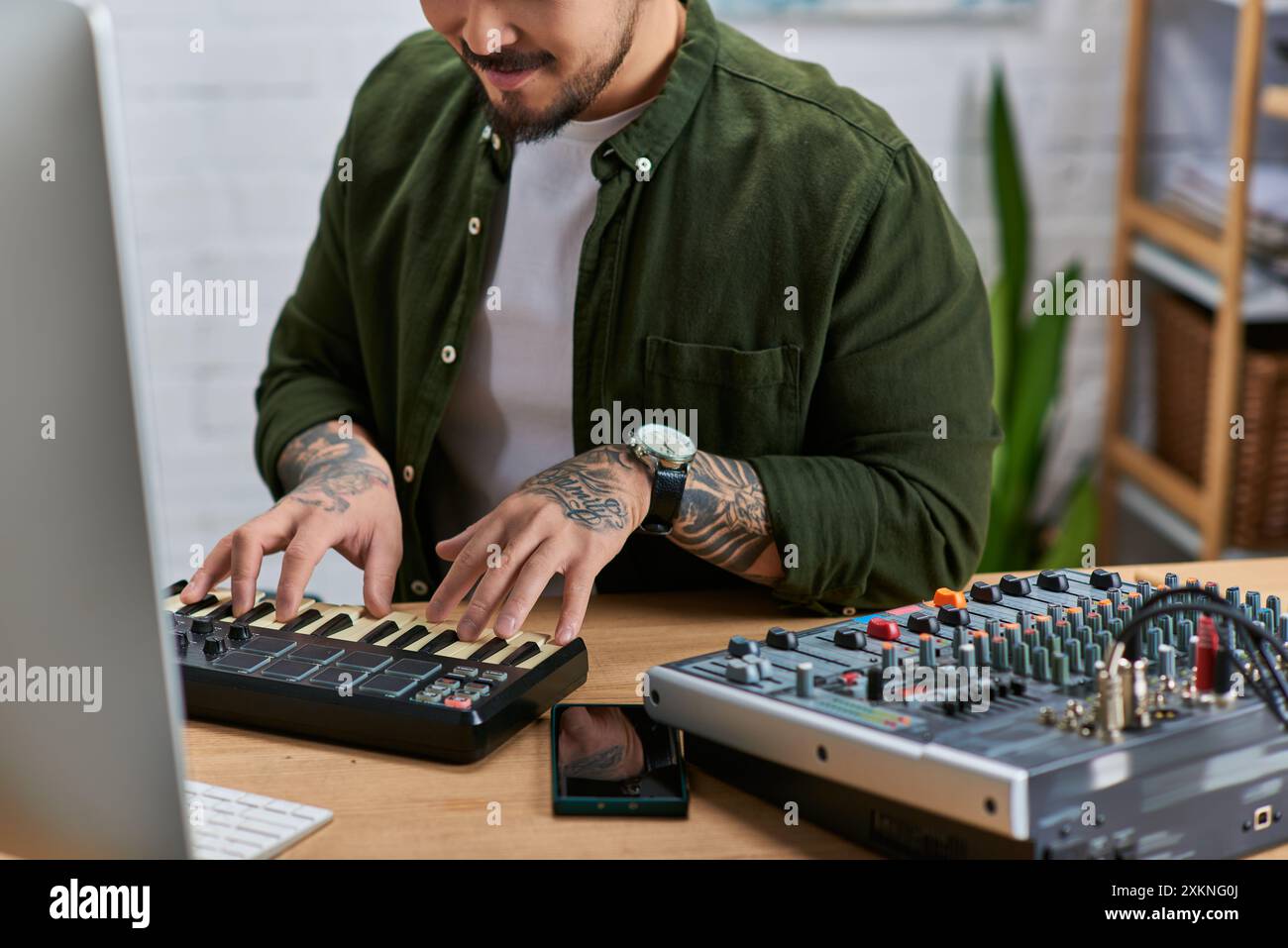 Ein gutaussehender asiatischer Mann spielt ein MIDI-Keyboard in seinem Studio. Stockfoto