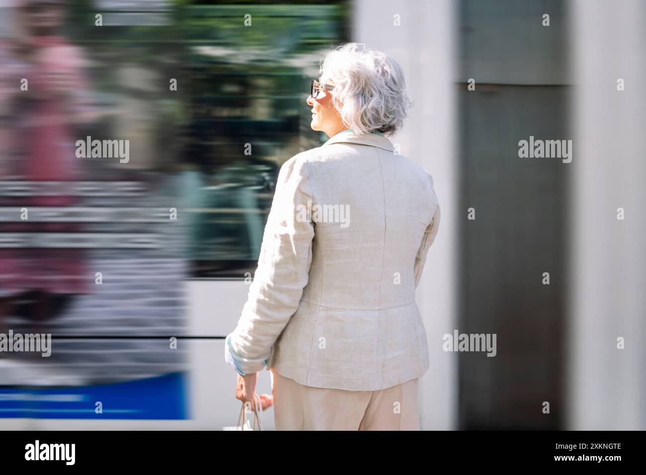 Rückansicht einer Reifen Frau, die den Bus vorbeifährt Stockfoto