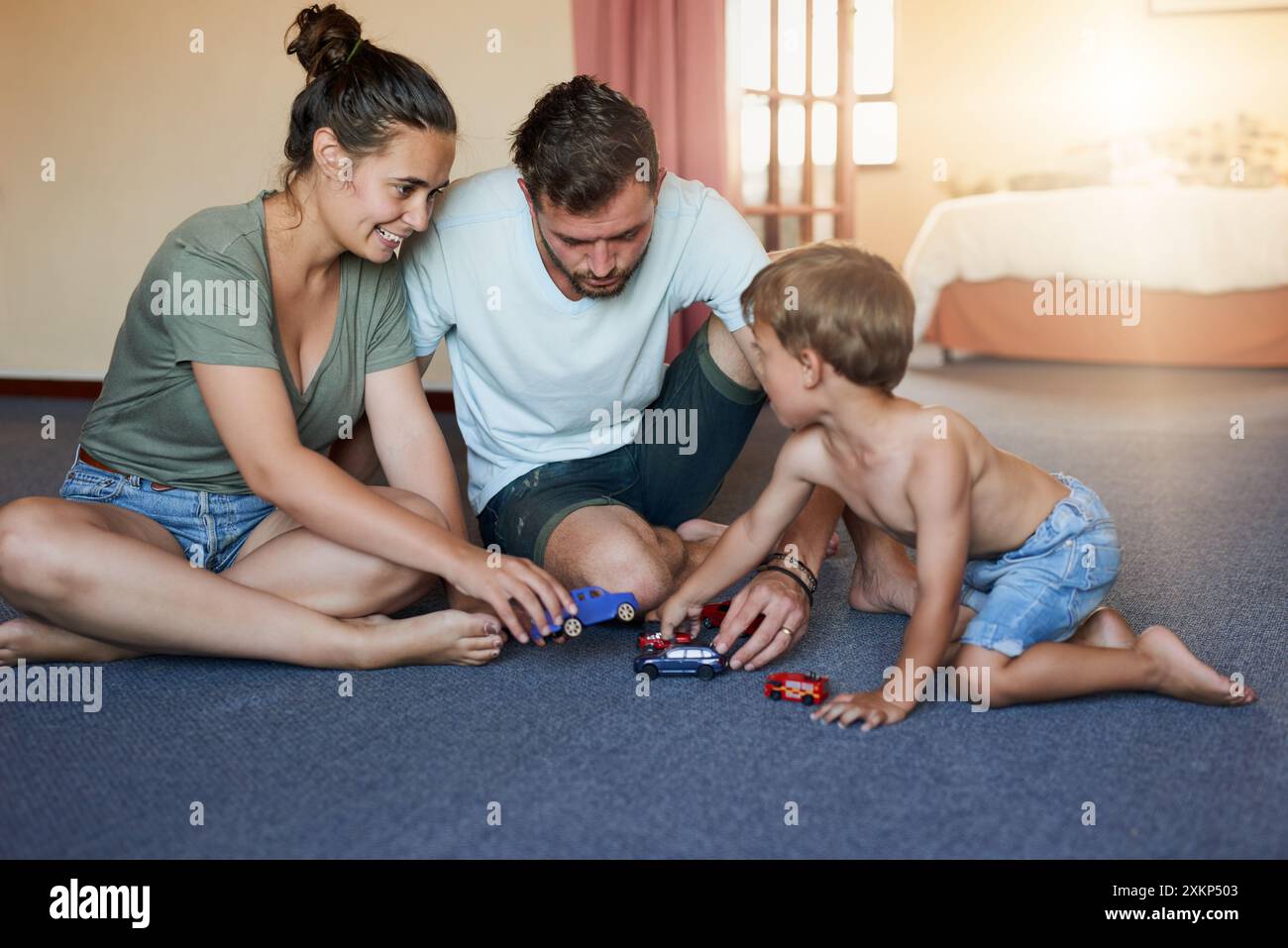 Heim, Mutter und Vater mit Kind mit Autospielzeug, Truck und verspielt zum Zusammenknüpfen am Wochenende. Mom, Dad und Junge mit Unterhaltung, Fantasie und Stockfoto