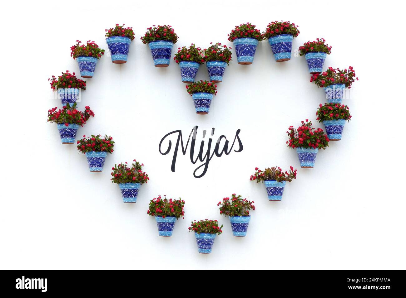 Nennen Sie Mijas, umgeben von Töpfen mit rot blühenden Pflanzen, die ein Herz bilden. Mijas ist eine schöne andalusische Stadt an der Costa del Sol. Spanien. Stockfoto