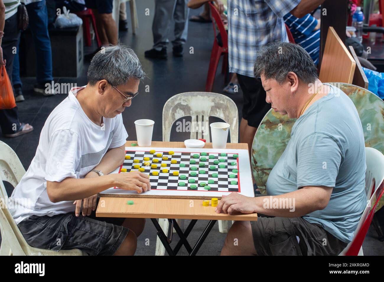 Zwei chinesische Männer mittleren Alters spielen gegeneinander in Chinatown, Singapur. Stockfoto