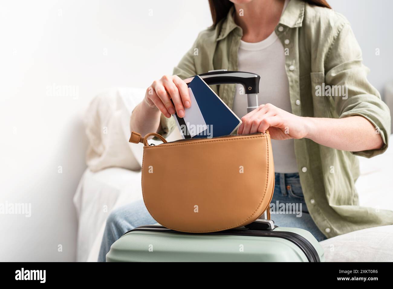 Eine junge Frau, die Reisepass und Kreditkarte in ihre Handtasche steckt, bevor sie ins Ausland reist. Sommerferien. Stockfoto