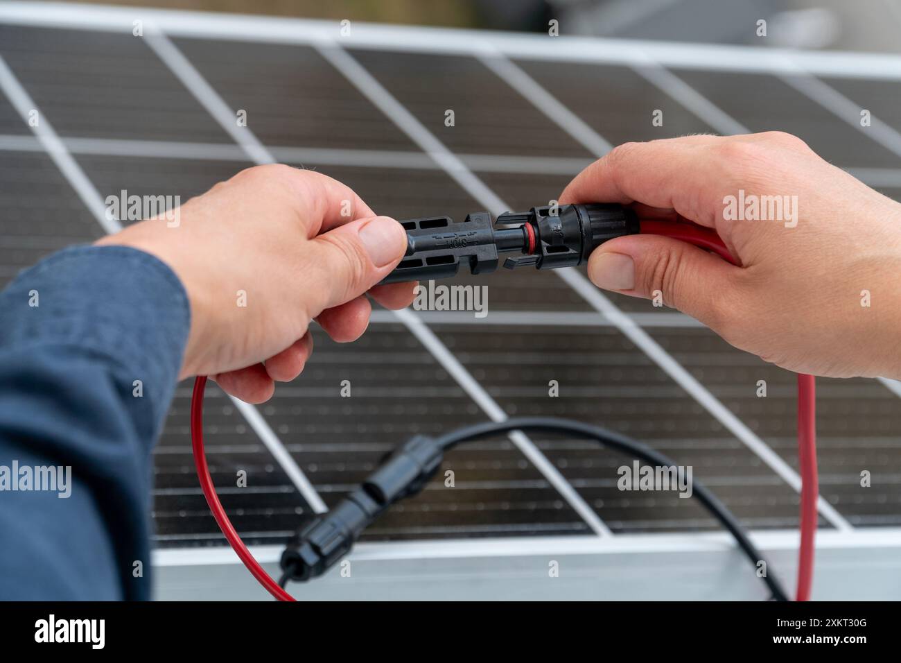 Nahaufnahme der Hände des Technikers, die mc4-Steckverbinder über dem Solarpanel verbinden. Erneuerbare Energien und Nachhaltigkeitskonzept Stockfoto