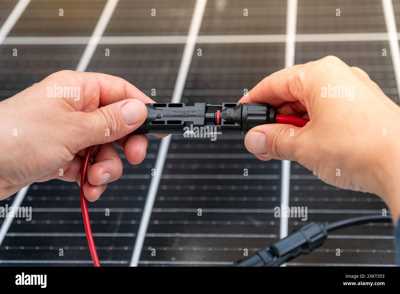 Nahaufnahme der Hände des Technikers, die mc4-Steckverbinder über dem Solarpanel verbinden. Erneuerbare Energien und Nachhaltigkeitskonzept Stockfoto