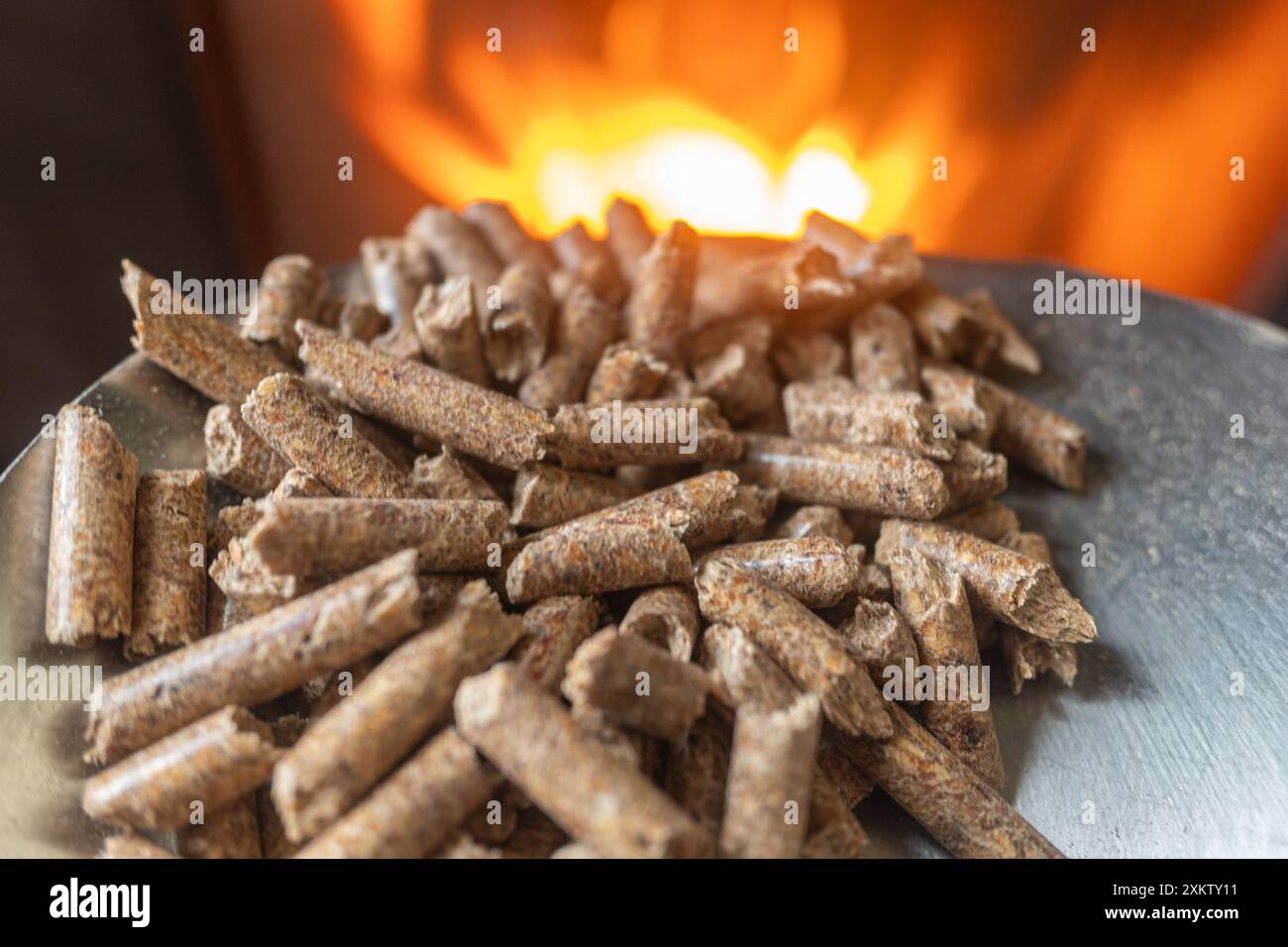 Holzsägespäne für Holzöfen, ökologischer Biokraftstoff mit Feuer im Hintergrund. Selektiver Fokus Stockfoto