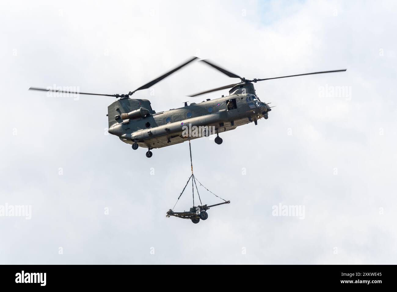 RAF Boeing Chinook Hubschrauber mit mittlerem Aufzug, der eine untersackte Last eines Feldgewehrs auf der Farnborough International Airshow 2024, Großbritannien, transportierte. Stockfoto