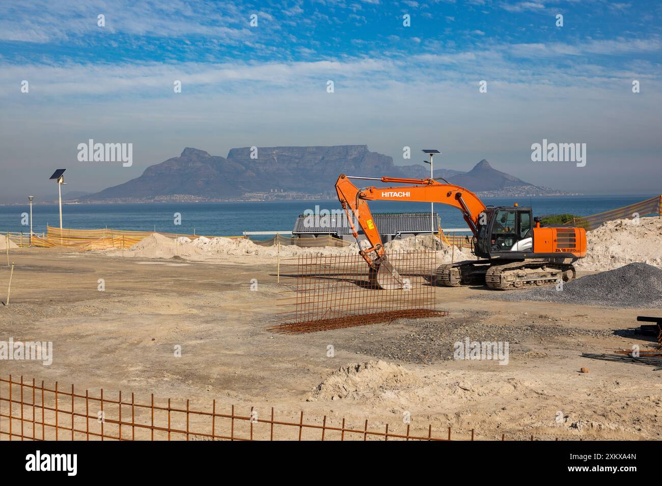 Strandbaustelle, die flach ist und für den Baubeginn in Blouberg Strand Kapstadt bereit ist. Hitachi Bagger vor Ort. Stockfoto