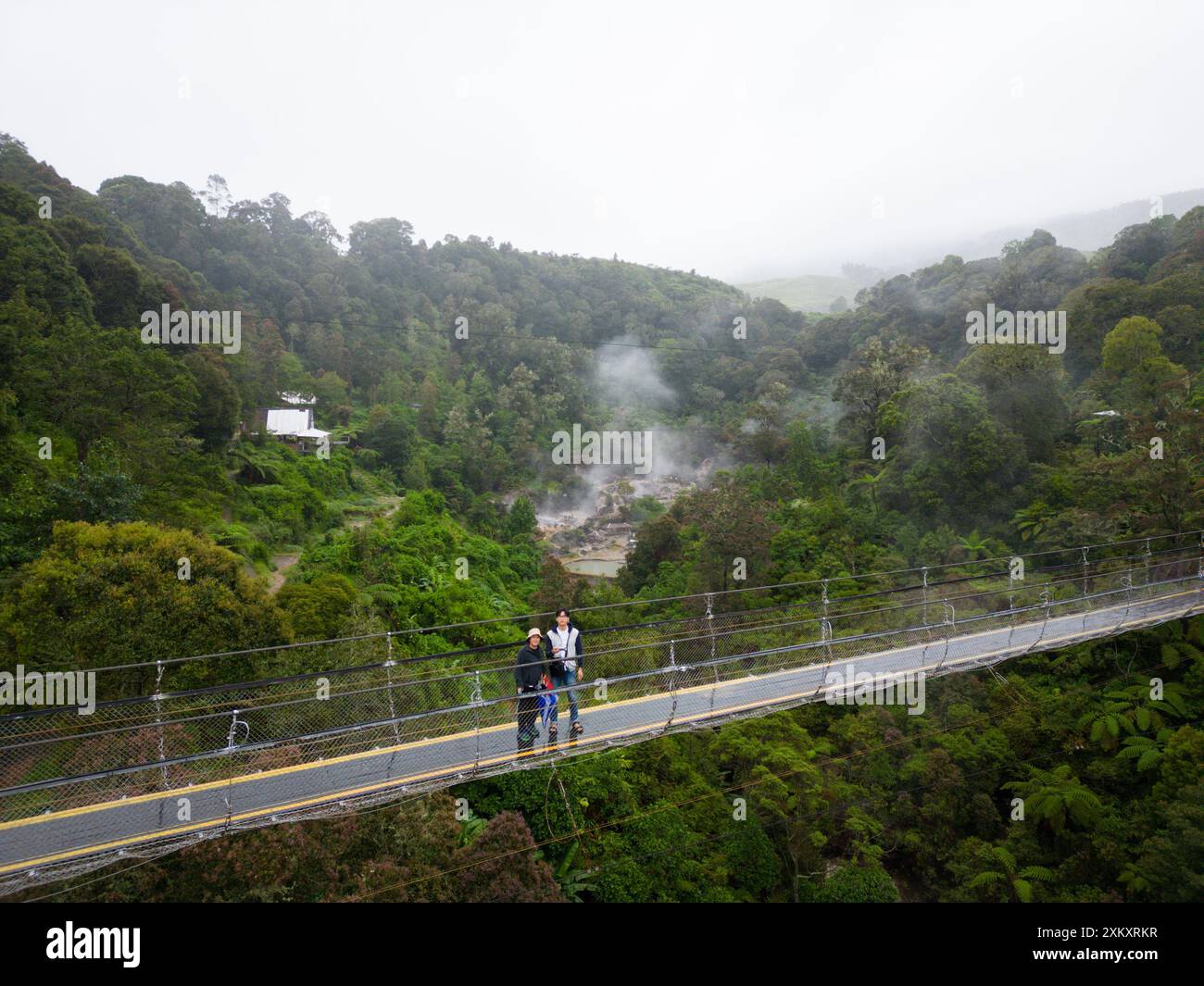 Touristen auf der Seilhängebrücke mit Blick auf den Wald und das Misty Valley aus der Vogelperspektive Stockfoto