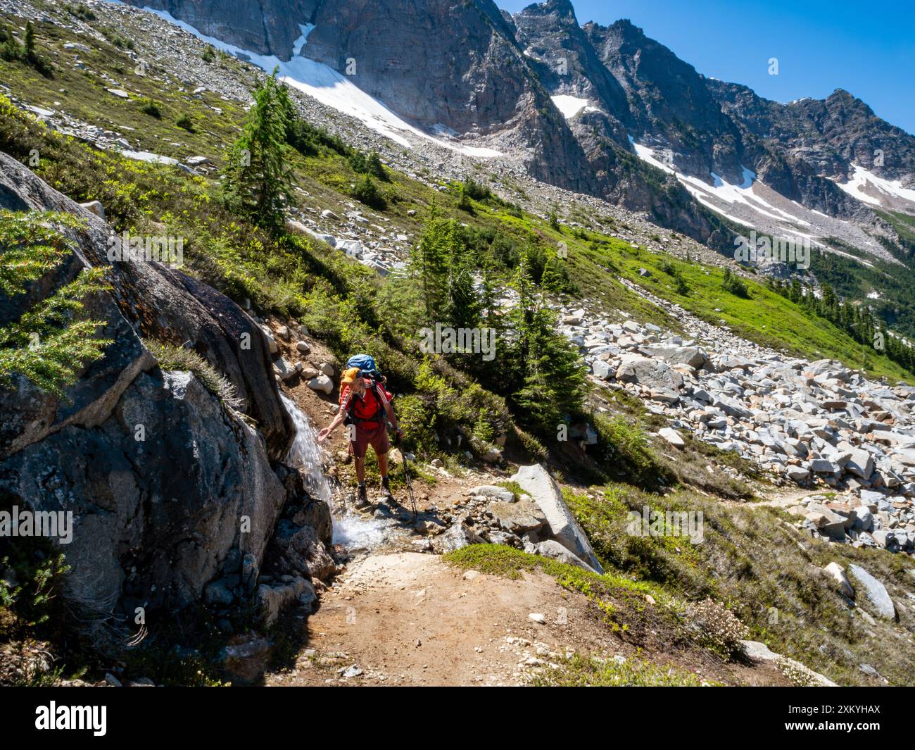 WA25556-00...WASHINGTON - PCT-Wanderer halten, um einen kleinen Wasserfall nördlich des Suiattle Pass in der Glacier Peak Wilderness zu besichtigen. Stockfoto