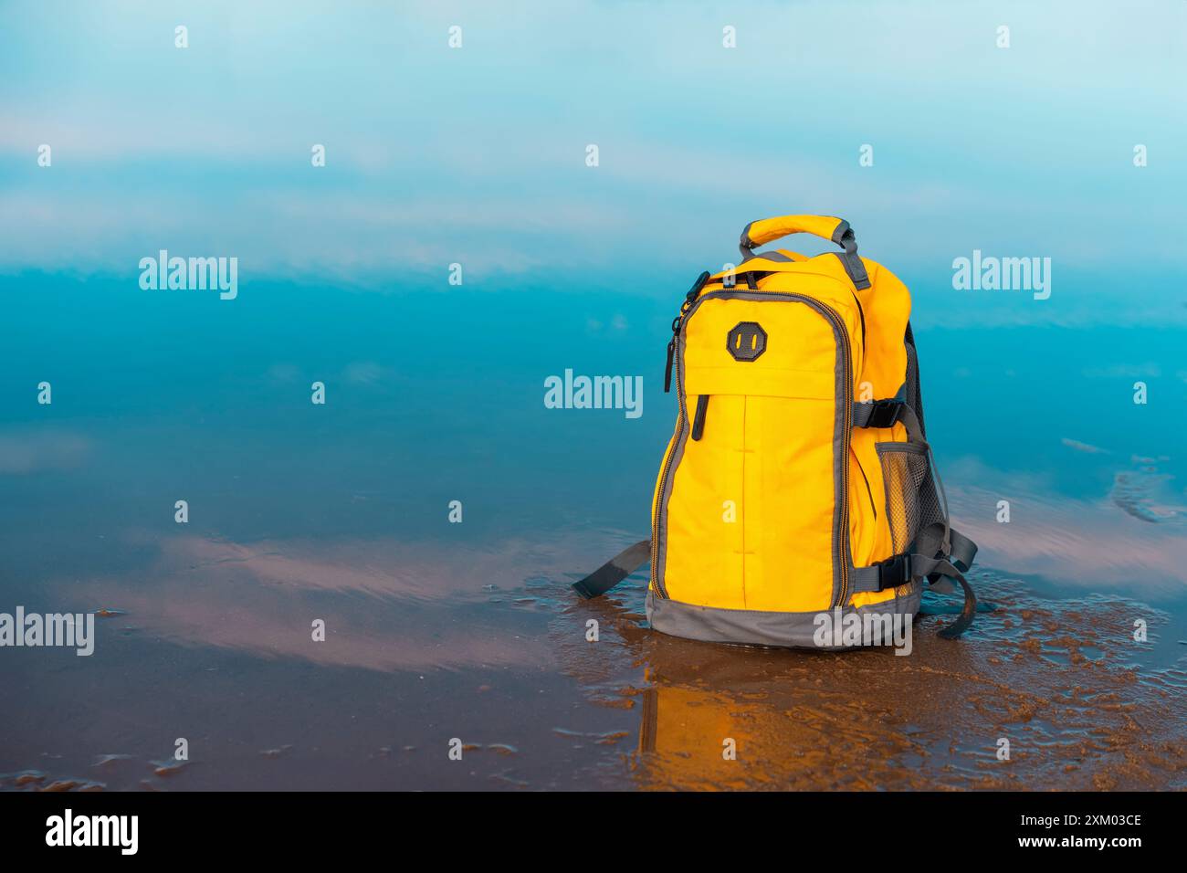 Gelber Rucksack am Meer gegen Meer bei traumhaftem Wetter. Reiseversicherungskonzept. Leichte Fahrt Stockfoto