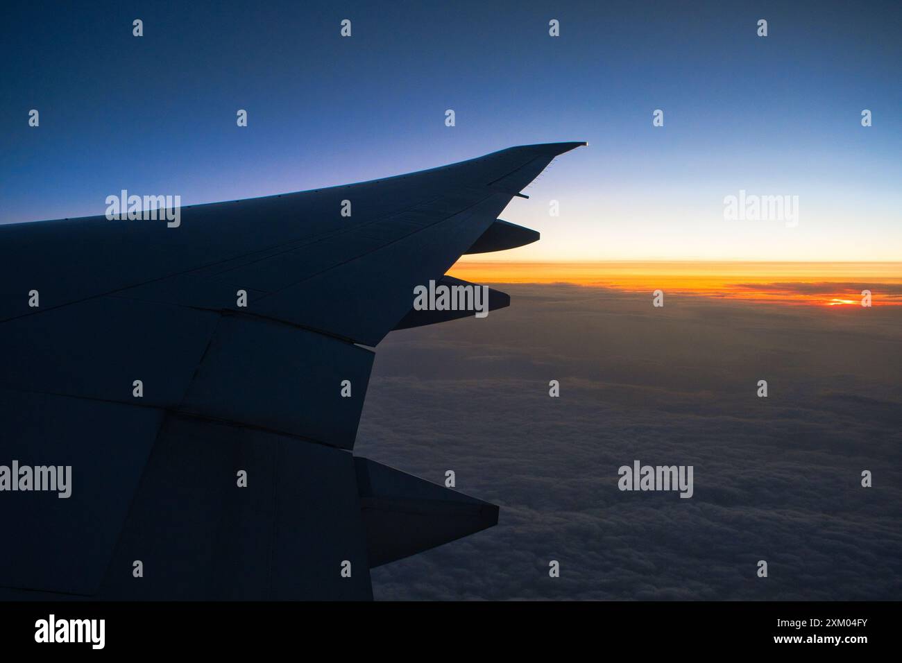 Ein rechter Flugzeugflügel, der vor einem Horizont mit einem Sonnenuntergang im Hintergrund reist und fährt. Stockfoto