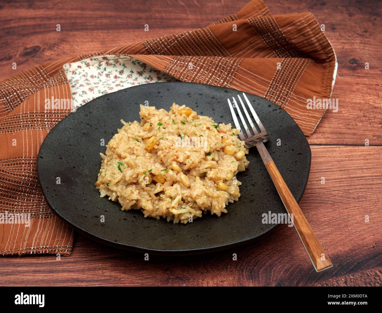 Eine Portion IC Pilav, ein traditionelles türkisches Reisgericht mit Johannisbeeren und Pinienkernen, präsentiert auf einem dunklen Teller Stockfoto