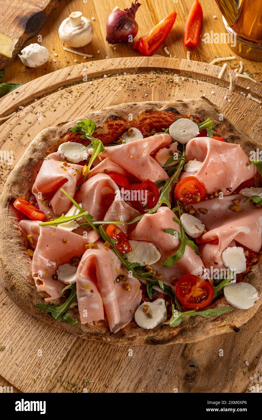 Appetitliche hausgemachte Pizza mit Mortadella, Aradel, Tomaten und Mozzarella auf einem Holzbrett Stockfoto