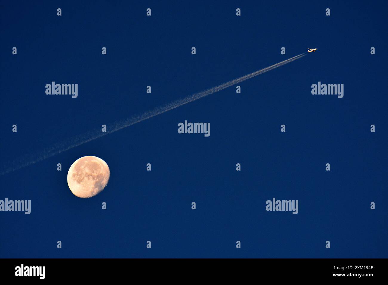 Marseille, Frankreich. Juli 2024. Ein Flugzeug mit seiner Treibstoffspur überquert den Himmel mit dem Mond dahinter. Quelle: SOPA Images Limited/Alamy Live News Stockfoto