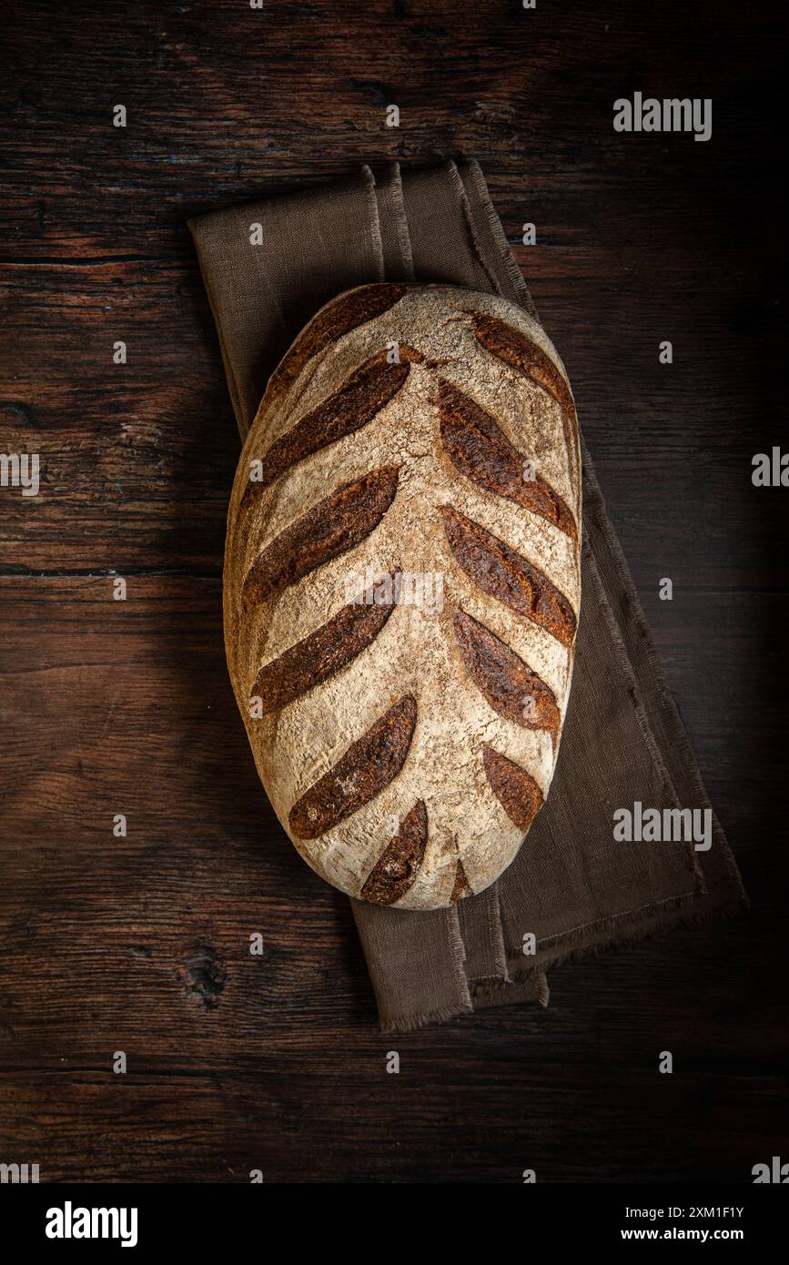 Sauerteigbrot. Frisch gebackenes Bio-Weizenbrot auf dunklem Hintergrund, mit Leinentischdecke. Draufsicht, Kopierraum. Stockfoto