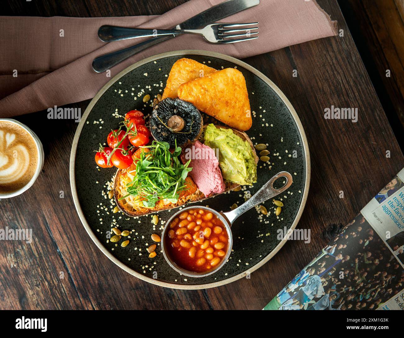 Englisches Frühstück auf einem schwarzen Keramikteller. Holztisch. Komplettes englisches Frühstück. Stockfoto