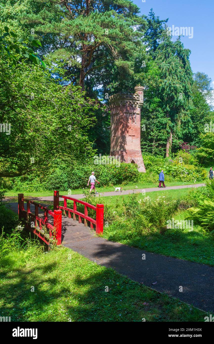 Upper Gardens, Bournemouth, Großbritannien - 10. Juli 2024: Rote Fußgängerbrücke über den Bourne Stream vor dem Bournemouth Gardens Water Tower. Stockfoto