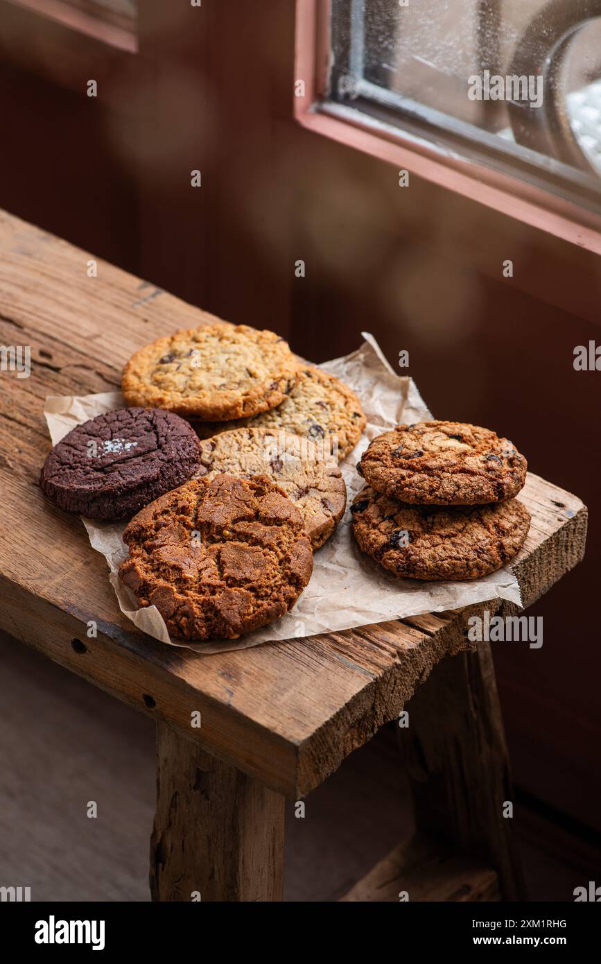 Handgemachte, gemischte Kekse, Schokoladen-Chip-Kekse und Haferkekse auf Pergamentpapier. Holztisch. Draufsicht. Stockfoto
