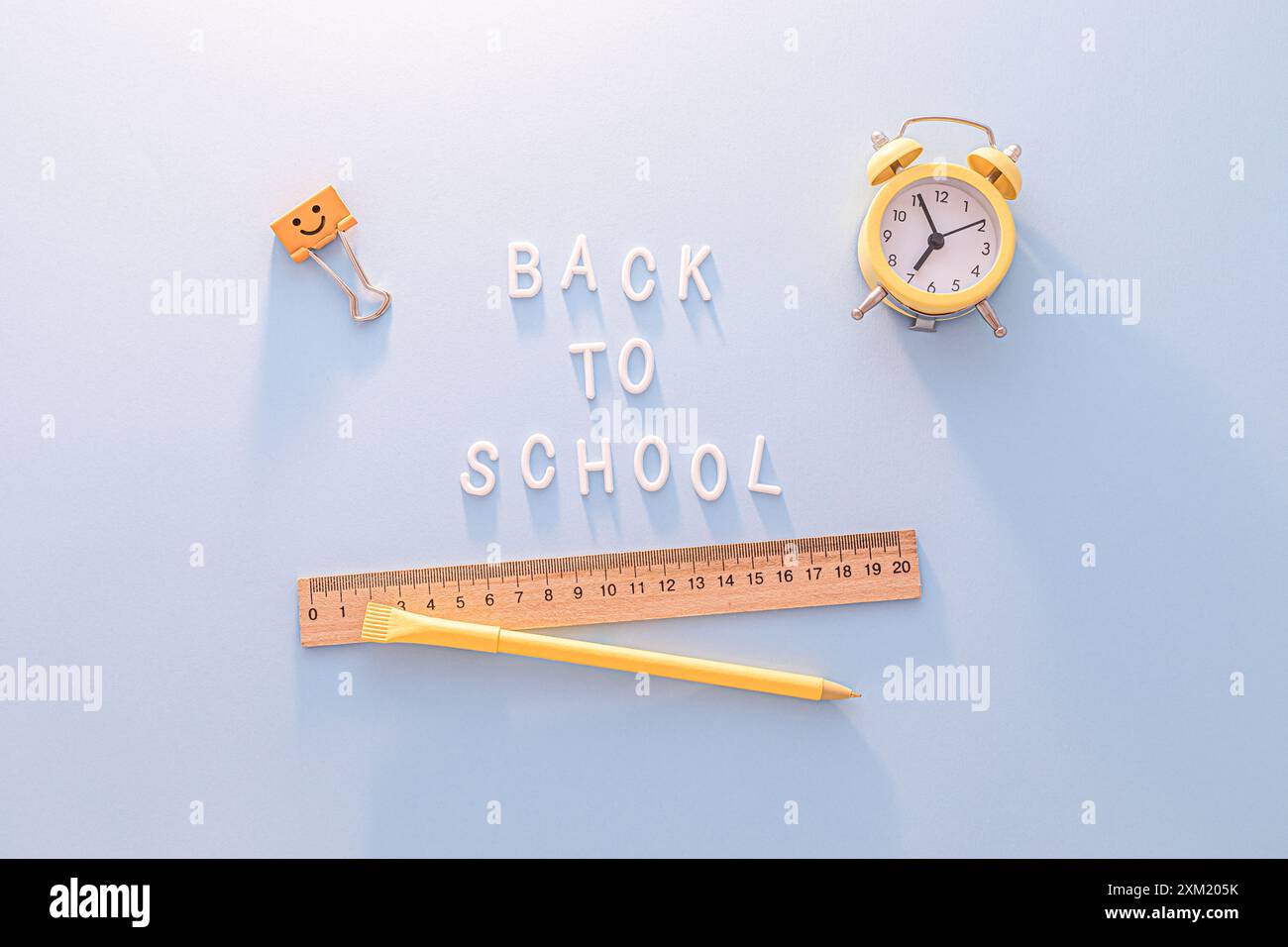 Zurück zur Schule. Gelber Wecker, Lineal und Stift auf blauem Hintergrund Stockfoto