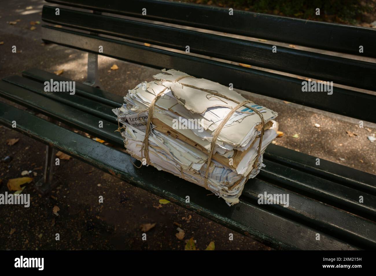 Ein Bündel alter Papiere auf einer Parkbank im Herbst. Armutsressourcenkonzept Stockfoto