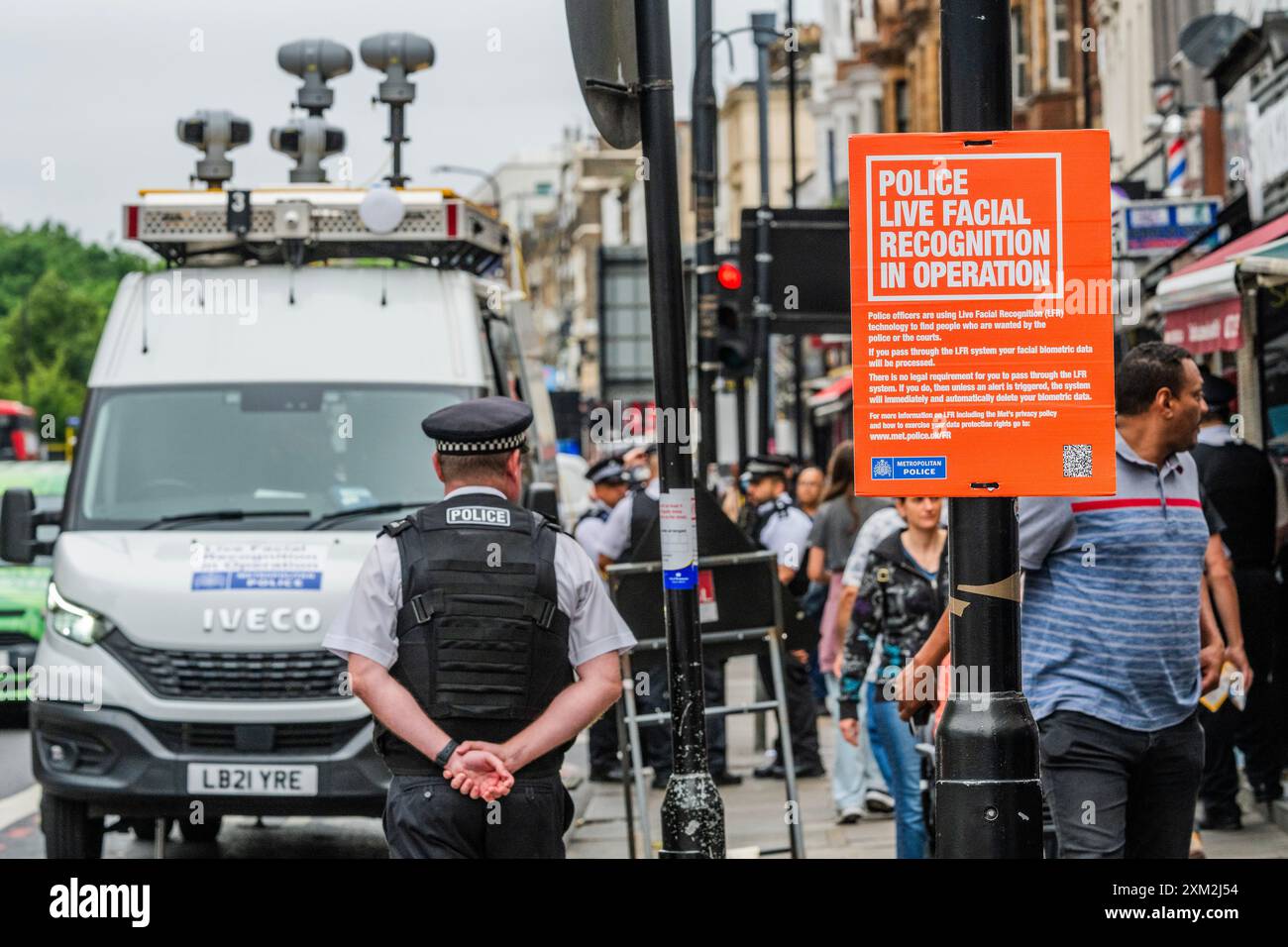 London, Großbritannien. Juli 2024. MET Polizeibeamte benutzen einen Überwachungswagen, um ein Live-Gesichtserkennungsnetz durchzuführen, um Personen zu finden, die von der Polizei und/oder den Gerichten gesucht werden, an der Edgeware Road, London. Auf dem Schild steht, dass Sie nicht durch gehen müssen, und die Anwesenheit so vieler Polizisten bedeutet, dass jeder Täter sich gut in Sicherheit halten würde. Guy Bell/Alamy Live News Stockfoto