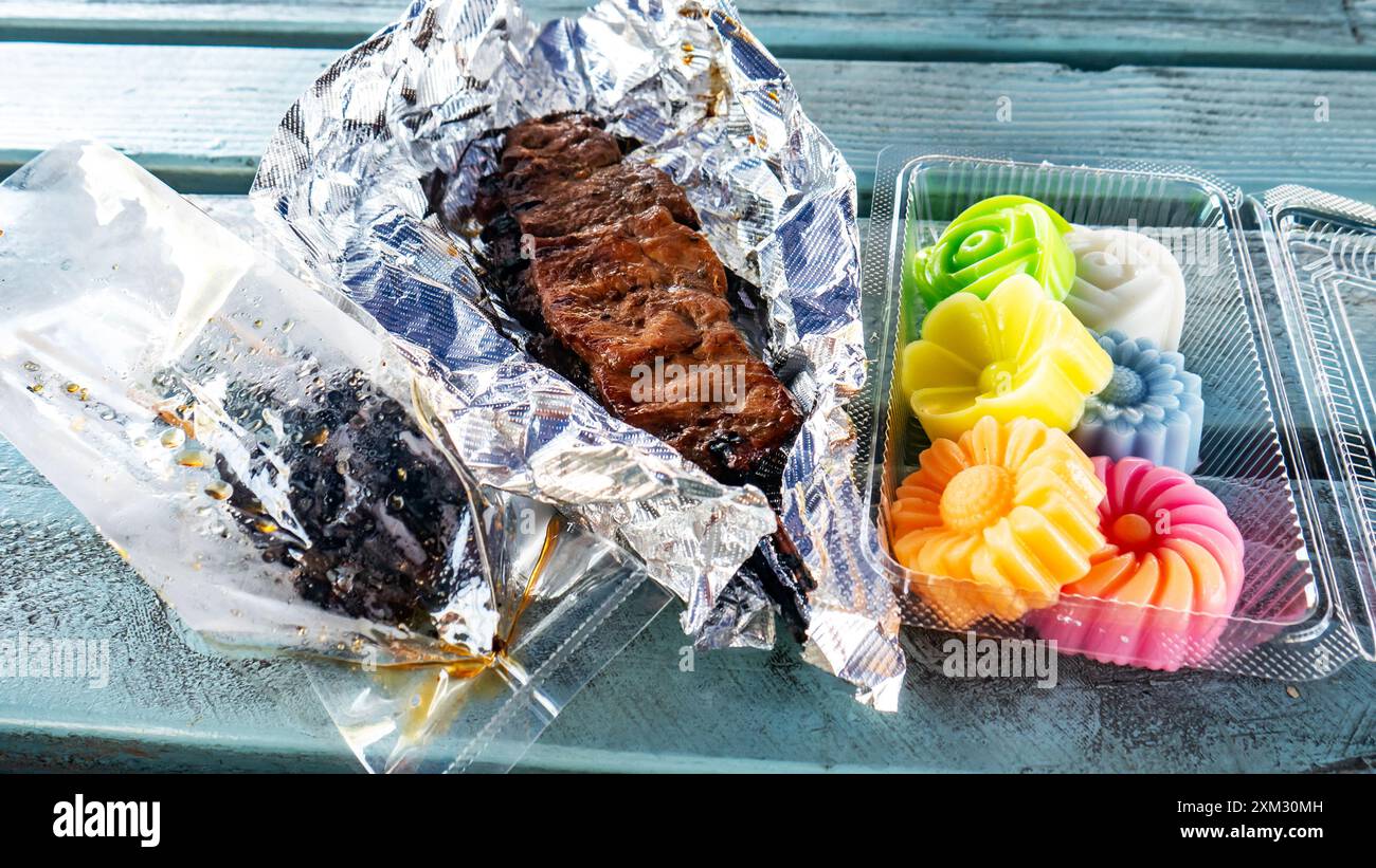Hühnerleberspieße, gegrillte Rindfleischspieße, Kokosmilchgelee (wun kathi) auf einem thailändischen Lebensmittelmarkt in LA, Kalifornien. Traditionelles thailändisches Street Food Stockfoto
