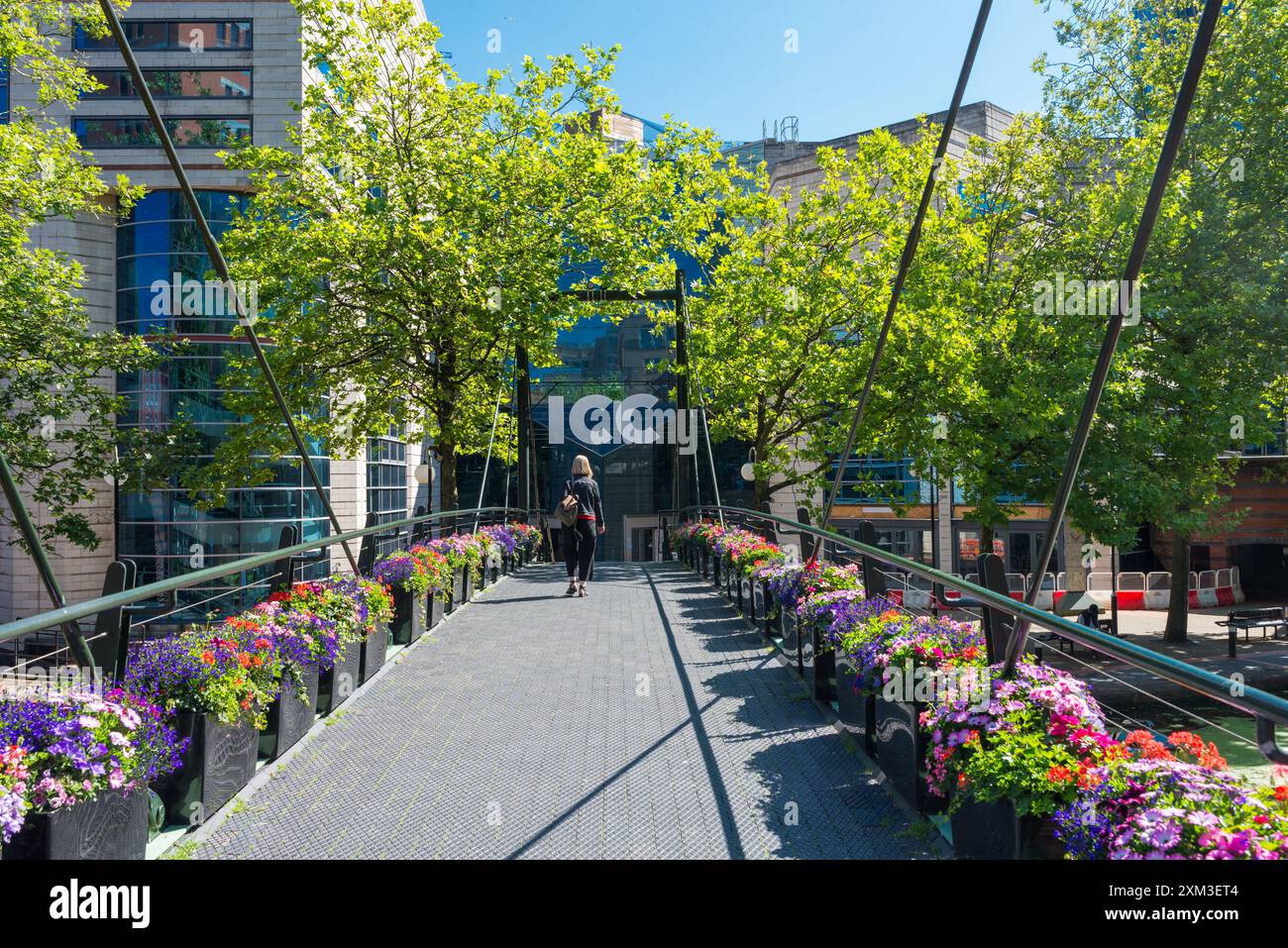 Fußgängerbrücke mit bunten Blumen über den Kanal zwischen dem Brindley Place und dem International Convention Centre ICC im Stadtzentrum von Birmingham Stockfoto