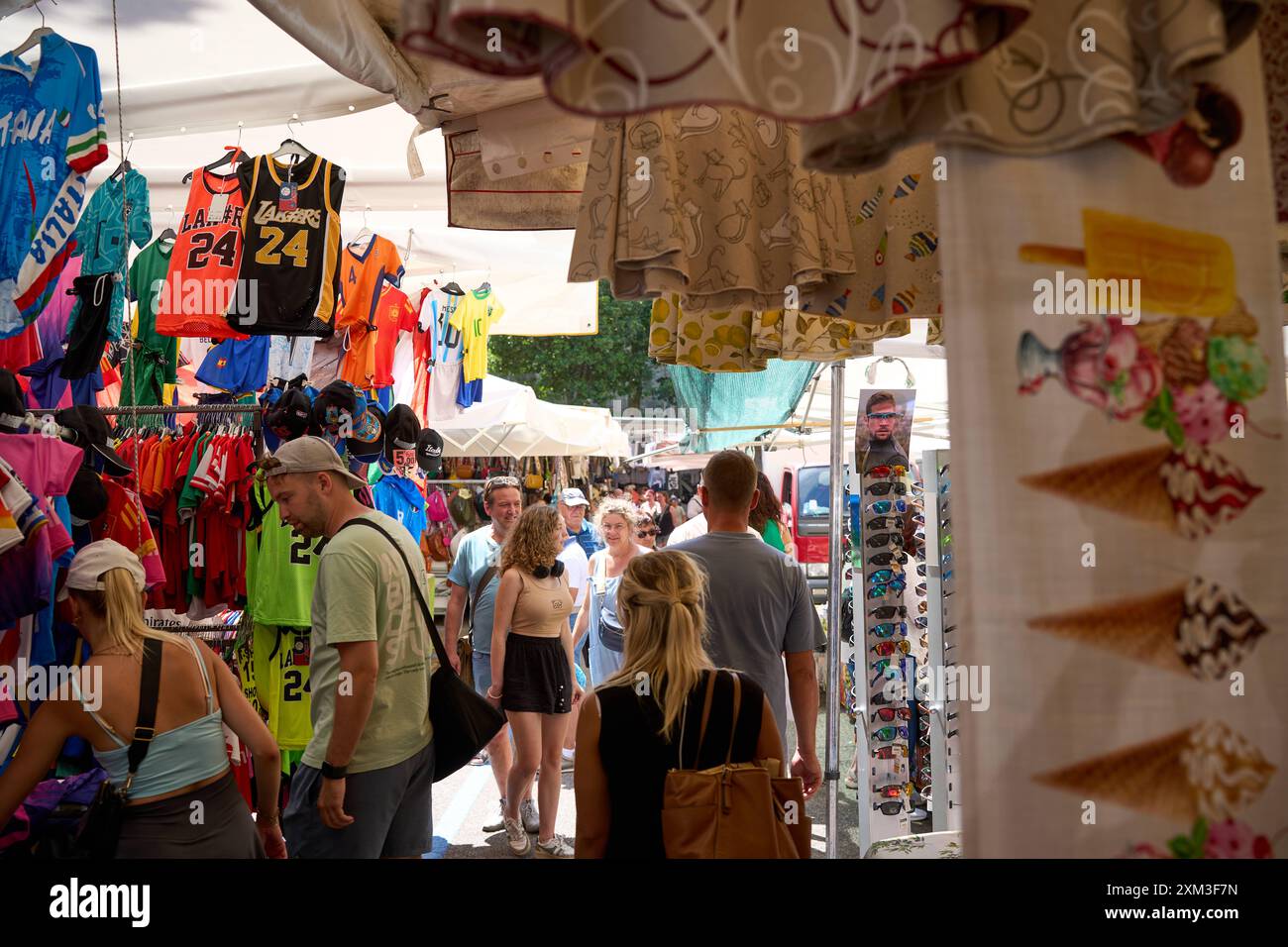 Malcesine, Gardasee, Italien - 20. Juli 2024: Wochenmarkt in Malcesine am Gardasee in Italien. Viele Besucher, darunter Touristen und Einheimische, die ein Schnäppchen suchen *** ein Wochenmarkt in Malcesine am Gardasee in Italien. Viele Besucher darunter Touristen und einheimische auf der Suche nach einem Schnäppchen Stockfoto