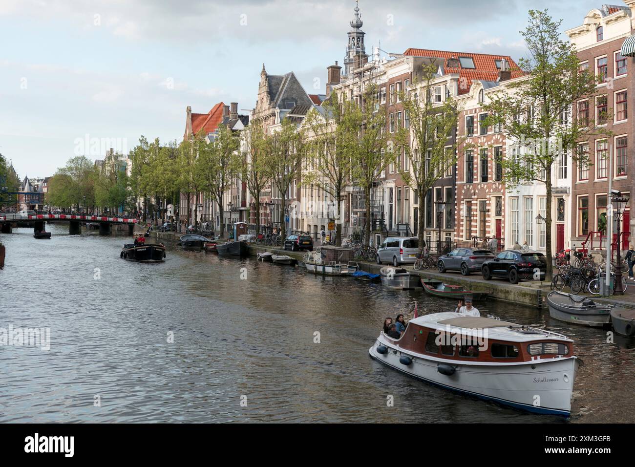 Ein Boot fährt entlang eines Kanals, der von alten traditionellen Amsterdamer Häusern im Zentrum von Amsterdam gesäumt ist. Stockfoto