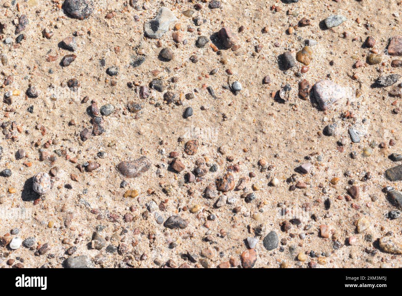 Kleine Steine sind in nassem Sand am Ufer der Ostsee, Blick von oben, natürliche Hintergrundfotos Stockfoto