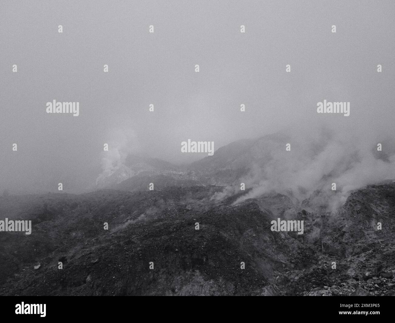 Eine nebelige Bergkette mit Nebel. Der Himmel ist dunkel und die Berge sind mit Schnee bedeckt Stockfoto