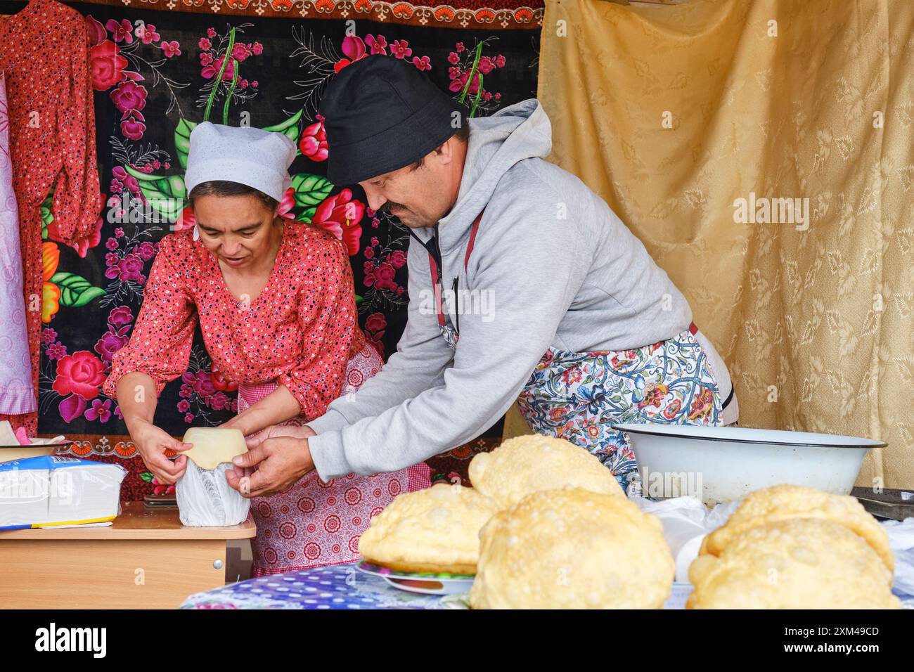 Kochkurs. Die asiatische Frau zeigt dem Mann, wie er Teig formt. Tatar gastronomisches Festival Sibirischer Baursak Stockfoto