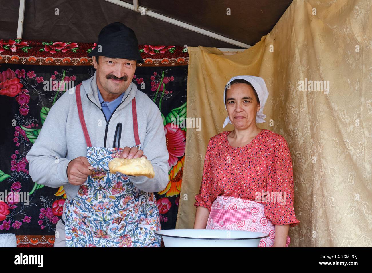 Kochkurs. Der Mensch hält Baursak. Eine Küchenfrau in der Nähe. Tatar gastronomisches Festival Sibirischer Baursak Stockfoto