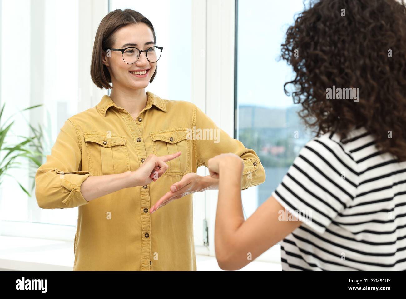 Junge Frauen, die Gebärdensprache für die Kommunikation in Innenräumen verwenden Stockfoto