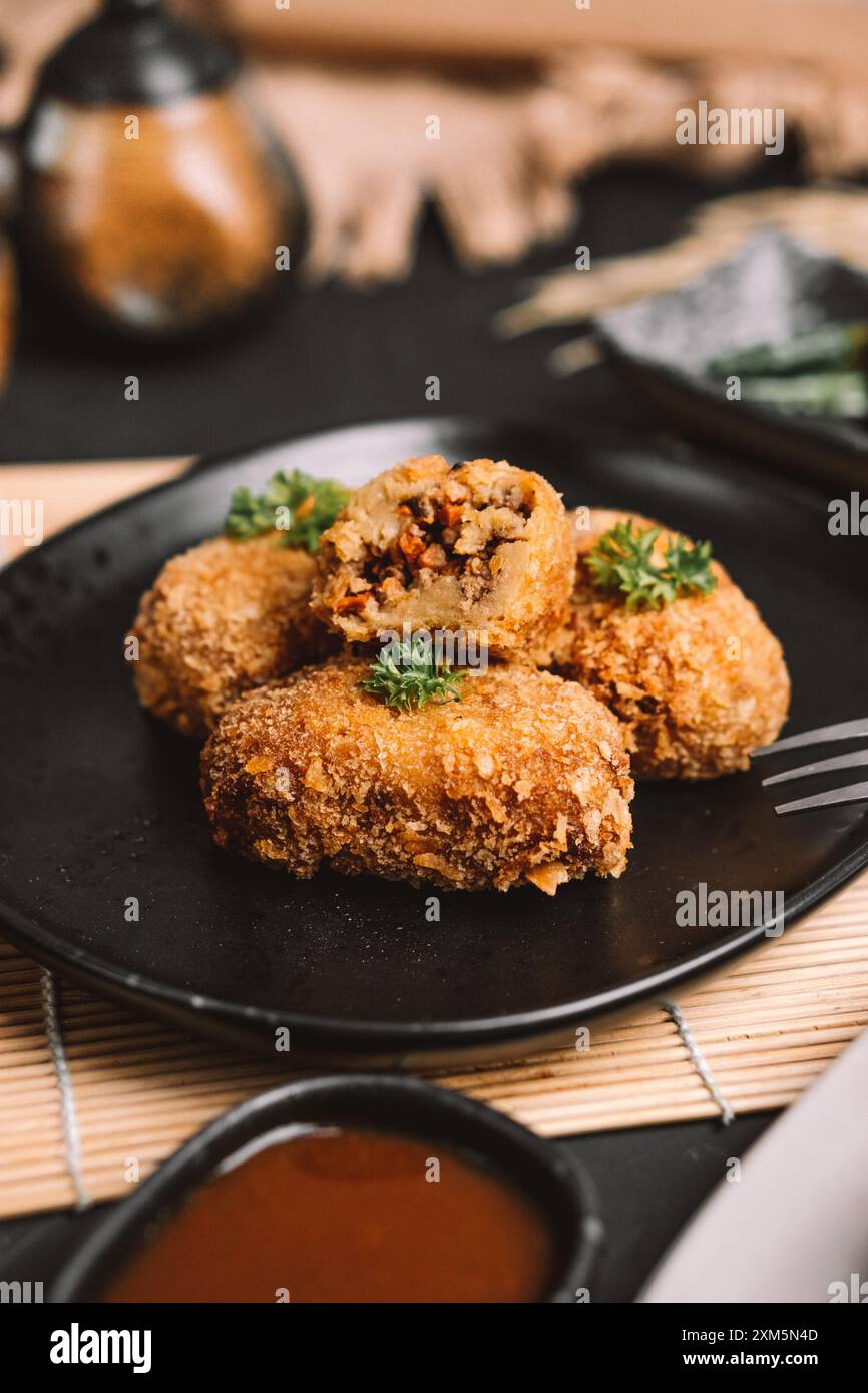 Ein Teller mit Lebensmitteln, der mehrere Kroketten enthält Stockfoto