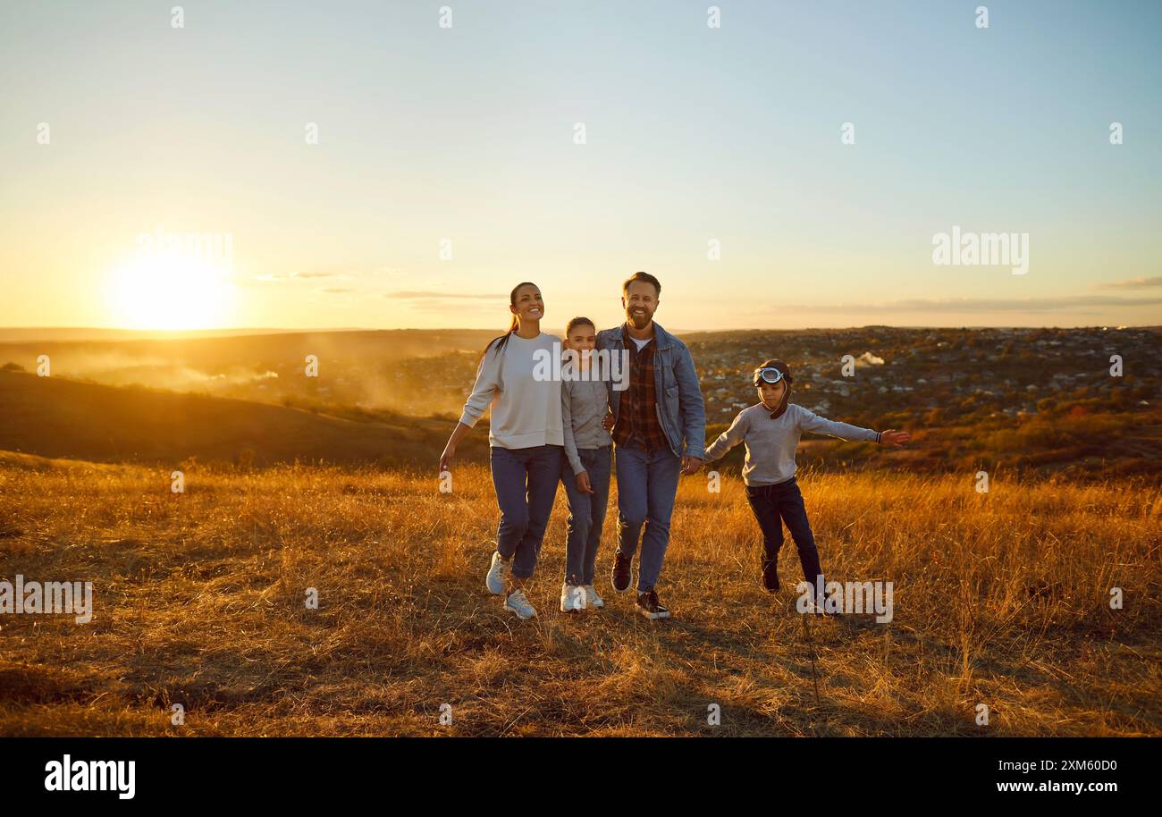 Glückliche Familie mit Kindern, die gemeinsam auf dem Feld spazieren gehen und die Natur im Freien genießen. Stockfoto