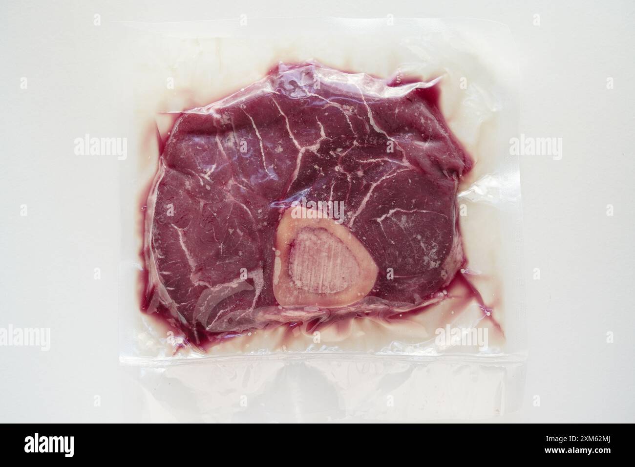 Großaufnahme von Bio-Rindfleisch (osso buco) in einer vakuumversiegelten Verpackung mit weißem Hintergrund Stockfoto