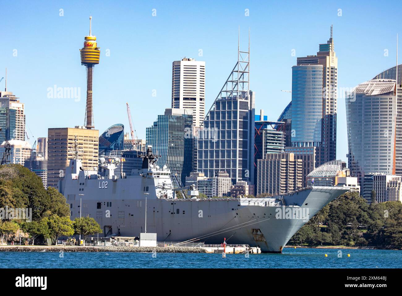 Hafen von Sydney, HMAS Canberra in Garden Island Marinestützpunkt mit Sydney Tower und Wolkenkratzern im Stadtzentrum dahinter, New South Wales, Australien Stockfoto