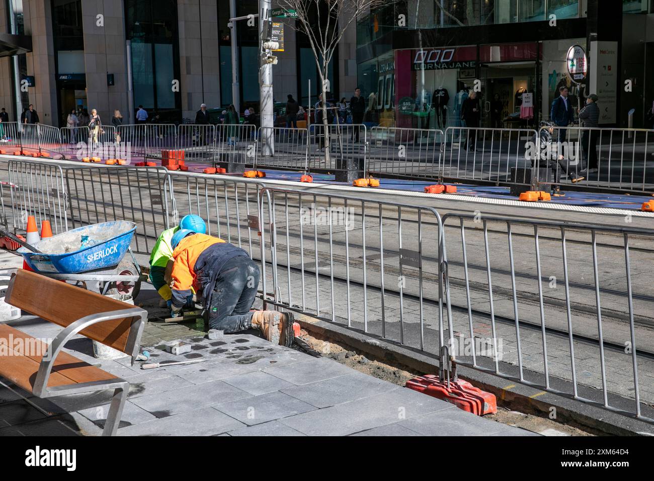 Sydney, Australien, der rat gibt Menschen, die neue Fußwege entlang der George Street im Stadtzentrum legen und auf den Knien arbeiten, um Platten zu legen Stockfoto