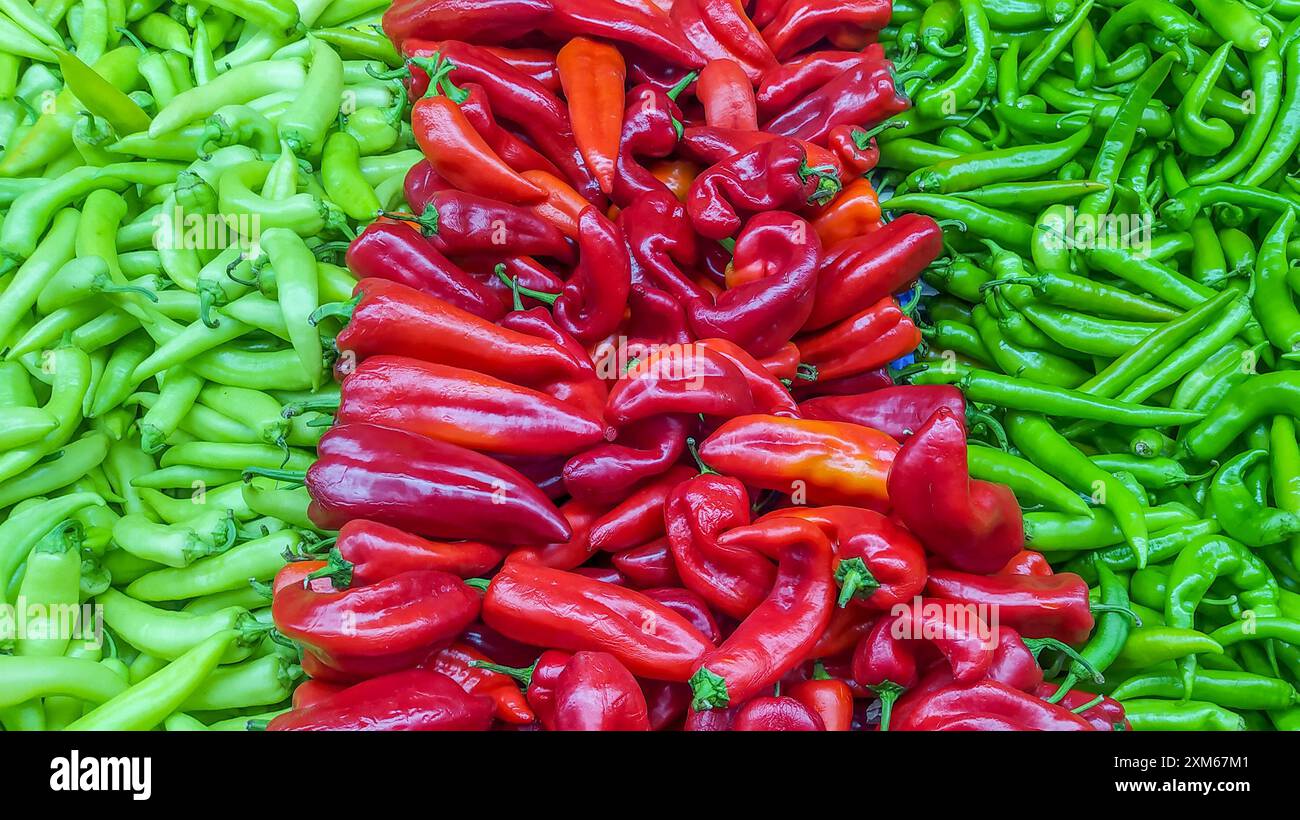 Frische grüne und rote Paprika auf einem Gemüsemarkt, symbolisiert Lebendigkeit und Fülle. Stockfoto