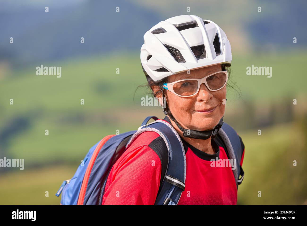 Porträt einer netten Seniorin mit Fahrradhelm, Rucksack und Sportkleidung Stockfoto