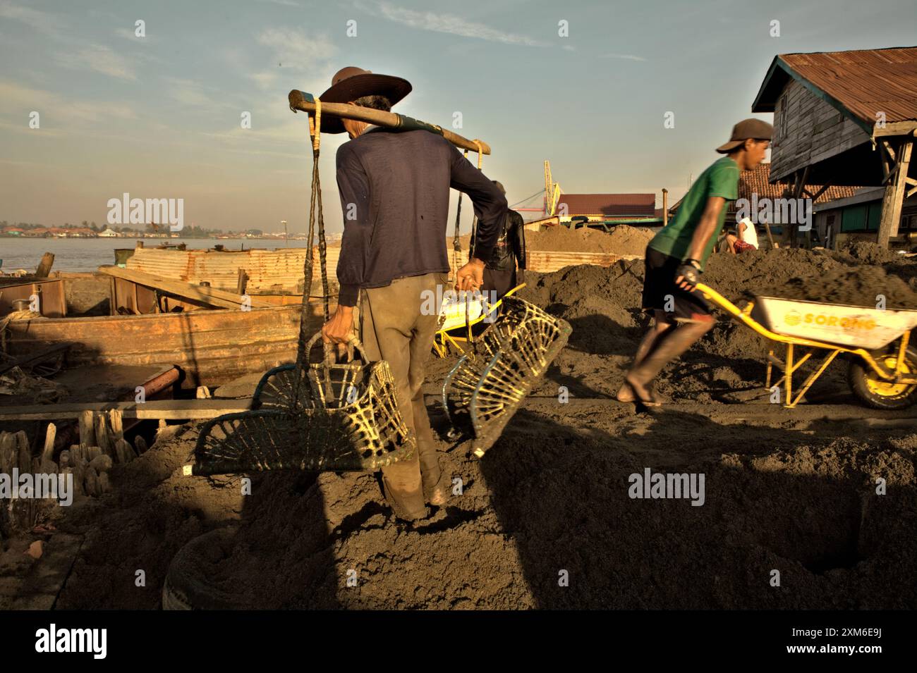 Arbeiter entladen Sand von einem Lastkahn auf das Ufer des Flusses Musi in Palembang, Südsumatra, Indonesien. Stockfoto