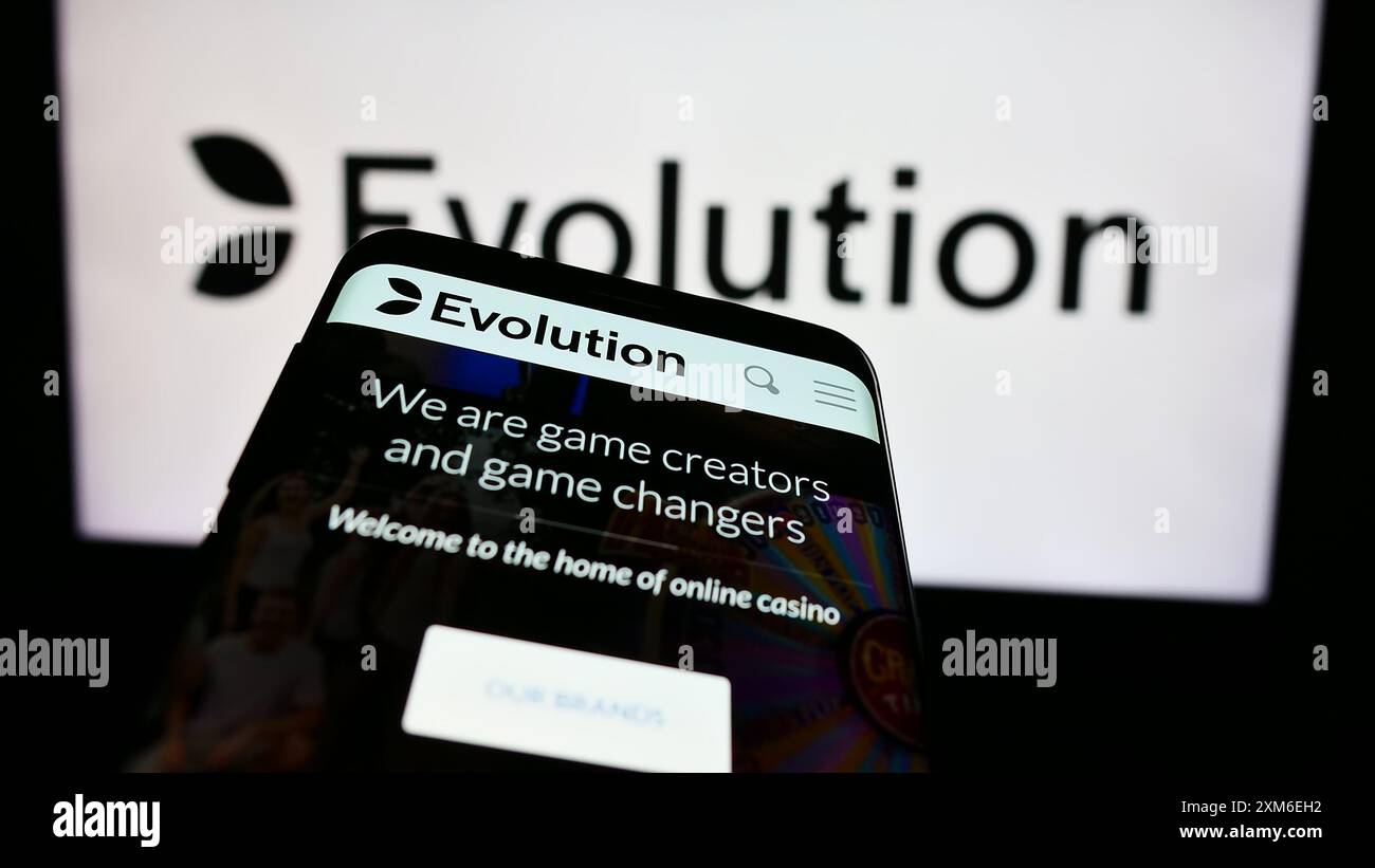 Mobiltelefon mit Website des schwedischen Glücksspieltechnologieunternehmens Evolution ab vor dem Geschäftslogo. Fokussieren Sie sich oben links auf der Telefonanzeige. Stockfoto