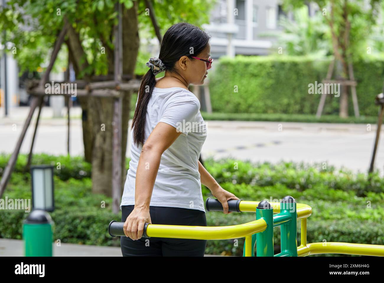 Asiatische Frau, die auf Ellipsentrainer im Public Park trainiert Stockfoto