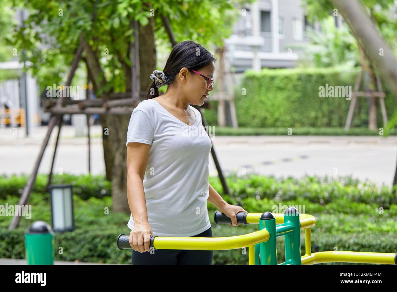 Asiatische Frau, die auf Ellipsentrainer im Public Park trainiert Stockfoto