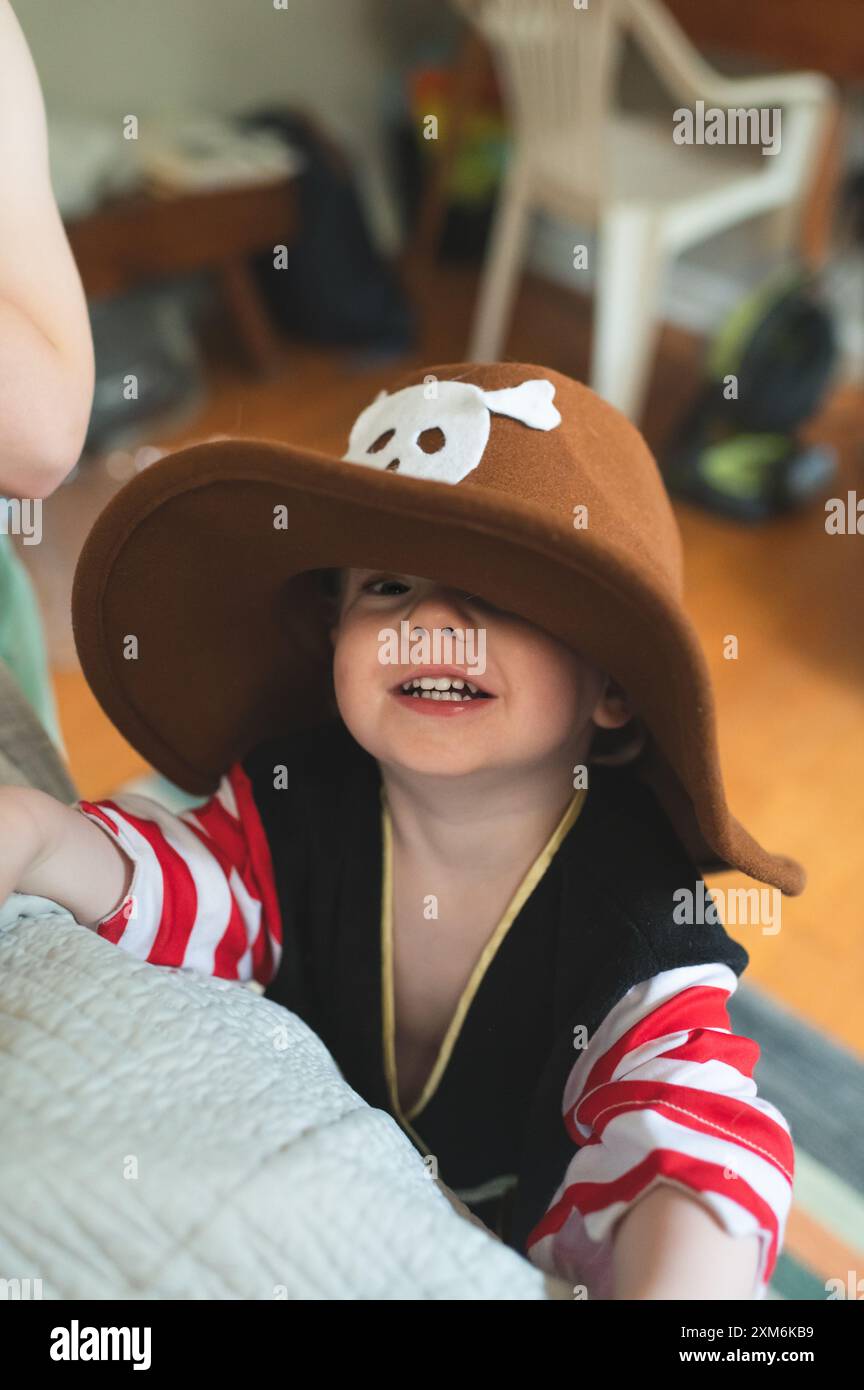 Ein kleiner Junge im übergroßen Piratenkostüm und Hut lächelt in die Kamera. Stockfoto