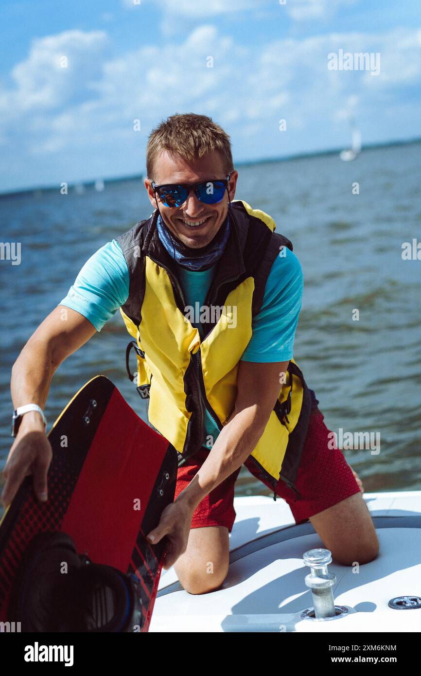 Ein Mann lädt Wakeboard-Ausrüstung auf ein Boot. Stockfoto