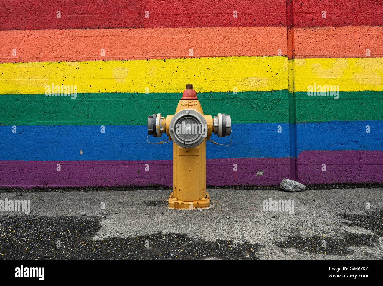 Hydrant vor einer farbenfrohen Wand mit Regenbogenfarben Stockfoto