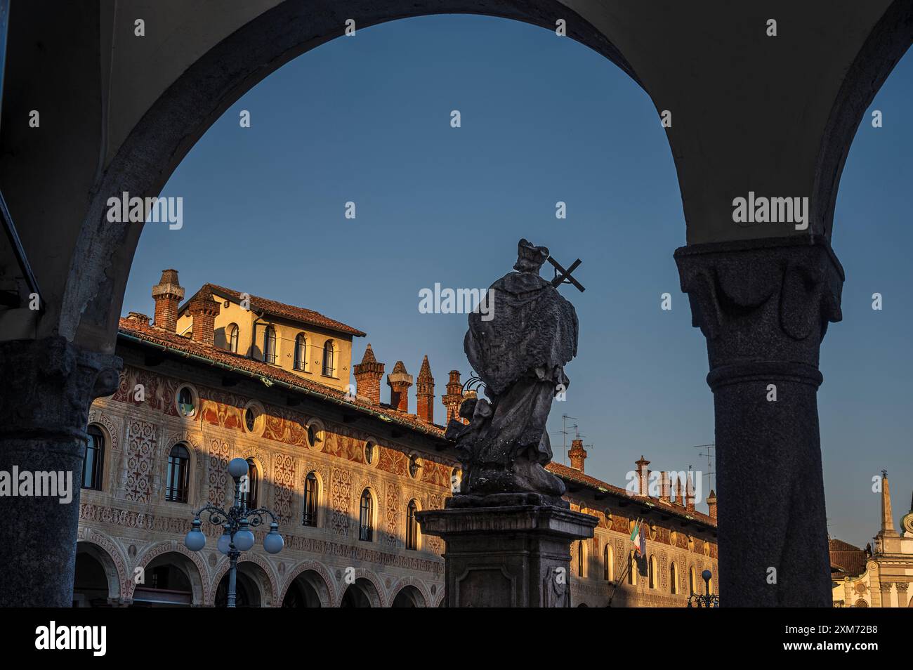Blick durch Arkaden zur Piazza Ducale mit der Kathedrale von Vigevanono Cattedrale di Sant&#39;Ambrogio am Ende des Platzes, Vigevano, Provinz Pav Stockfoto