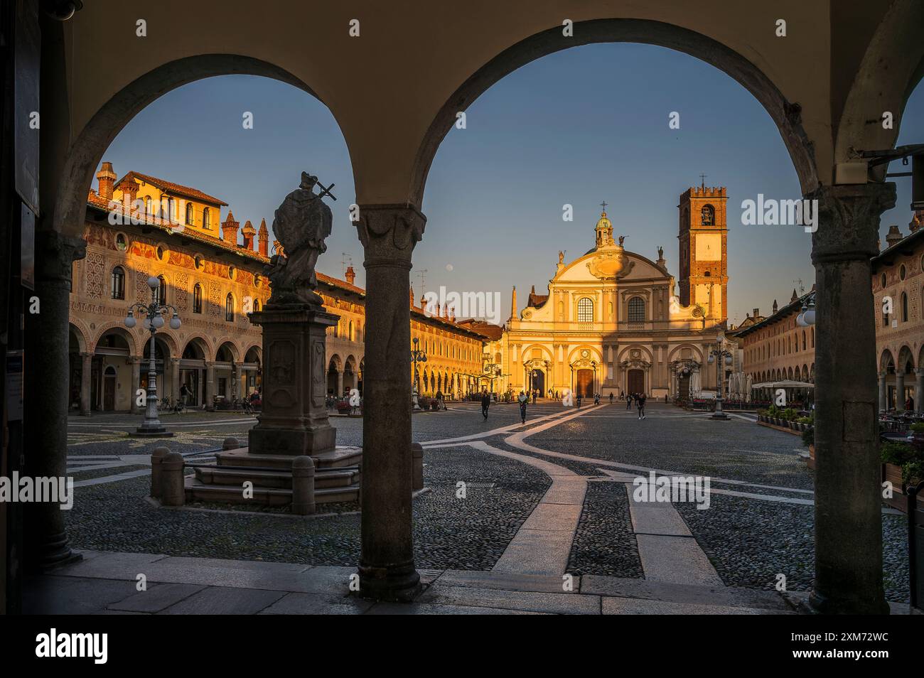 Blick durch Arkaden zur Piazza Ducale mit der Kathedrale von Vigevanono Cattedrale di Sant&#39;Ambrogio am Ende des Platzes, Vigevano, Provinz Pav Stockfoto